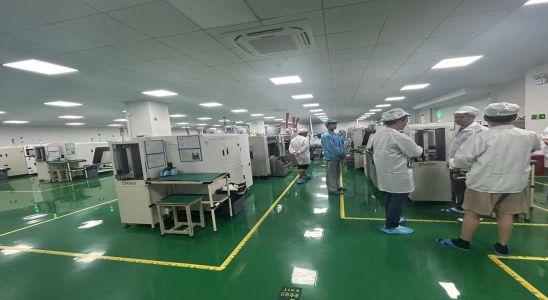 Automated Surface Mount Technology (SMT) machines placing components onto green PCB circuit boards for high-volume manufacturing.